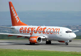 EasyJet airplane on the runway with an orange tail and 'easyJet.com' branding on the fuselage.