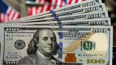 Hundred-dollar bills fanned out with an American flag in the background, showing Benjamin Franklin's portrait on the notes.