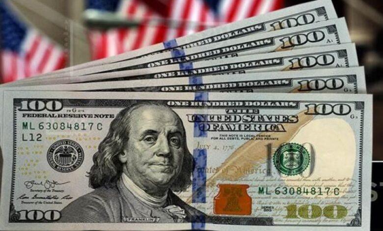 Hundred-dollar bills fanned out with an American flag in the background, showing Benjamin Franklin's portrait on the notes.
