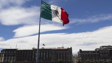 515155454541 | MCG24 | موقع إلكتروني مغربي شامل متجدد على مدار الساعة Mexican flag waving atop a tall flagpole in front of a large government building under a blue sky.