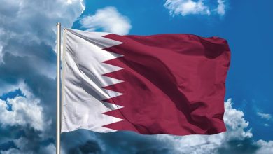 Qatar's flag waving in the wind against a blue sky.
