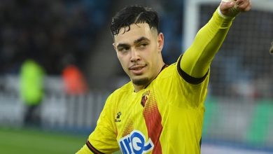 Soccer player in a yellow jersey points toward something off-camera on the field with a focused expression.