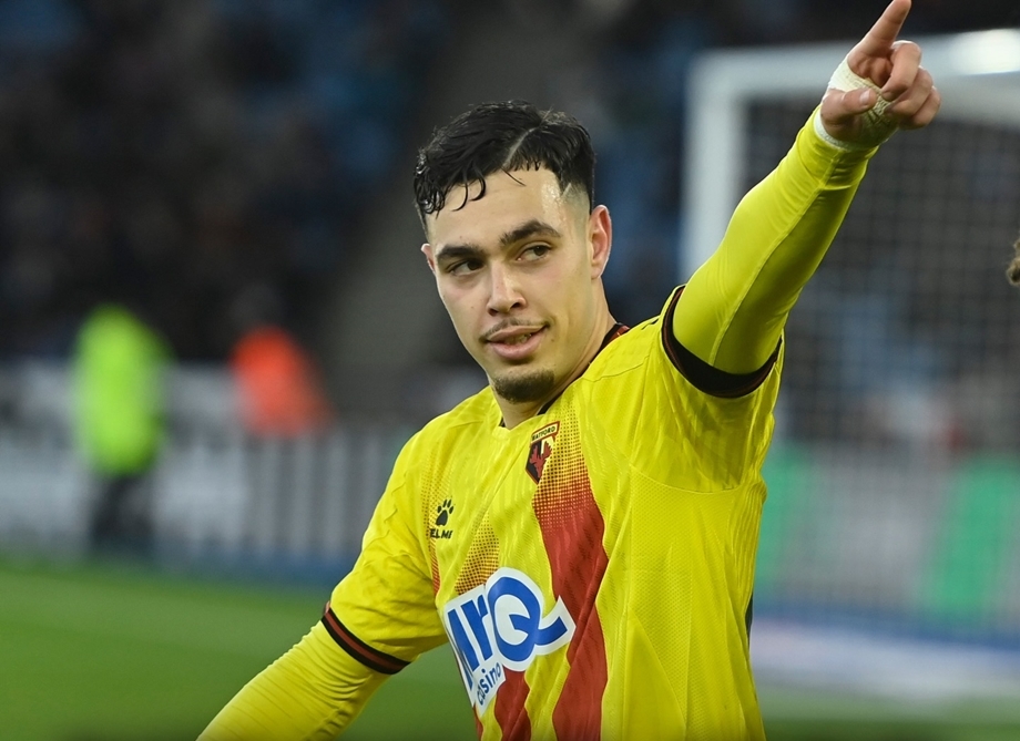 Soccer player in a yellow jersey points toward something off-camera on the field with a focused expression.