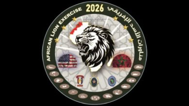 Circular emblem for African Lion Exercise 2026 featuring a roaring lion at center, with flags and unit insignia on a dark background