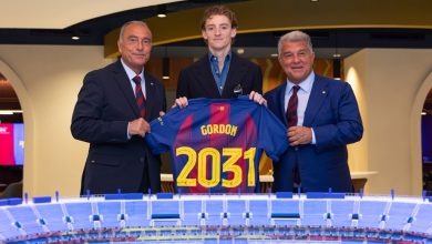 Three men in suits present a blue jersey labeled Gordon and 2031, standing behind a scale model stadium.