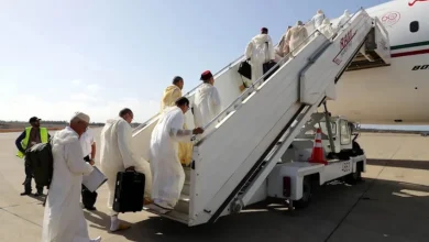 الحجاج-المغاربة | MCG24 | موقع إلكتروني مغربي شامل متجدد على مدار الساعة Group of travelers in white robes ascend a mobile boarding stair to a plane on the tarmac, carrying bags and suitcases.