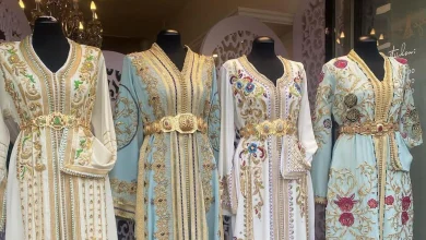 القفطان-المغربي | MCG24 | موقع إلكتروني مغربي شامل متجدد على مدار الساعة Group of four embellished, pastel-colored dresses on mannequins with gold embroidery and jeweled belts in a shop window display.