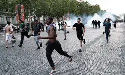 جماهير-باريس-سان-جيرمان | MCG24 | موقع إلكتروني مغربي شامل متجدد على مدار الساعة People sprint across a cobblestone street as smoke rises behind them, suggesting a chaotic scene in progress.
