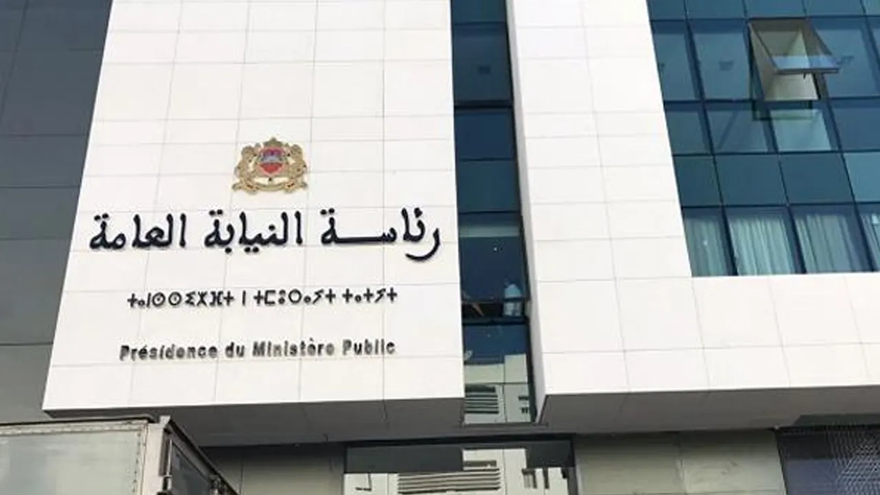 Facade of a government building with emblem and sign reading Arabic 'رئاسة النيابة العامة' and French 'Présidence du Ministère Public'.