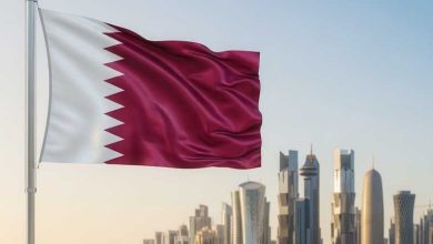 عيسى-1778411814169_large | MCG24 | موقع إلكتروني مغربي شامل متجدد على مدار الساعة Qatar national flag fluttering on a pole with Doha's modern skyline in the background.