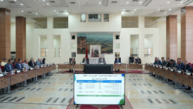 1000263336 | MCG24 | موقع إلكتروني مغربي شامل متجدد على مدار الساعة Large conference room with officials seated around U-shaped tables; a data presentation board sits at the front in the foreground.