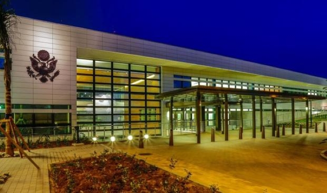 5487874 | MCG24 | موقع إلكتروني مغربي شامل متجدد على مدار الساعة Night exterior of a modern public building with a glass wall, emblem on the left, and a covered entrance.