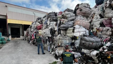 Guardia Civil officers inspect a massive pile of bundled clothes outside a warehouse.