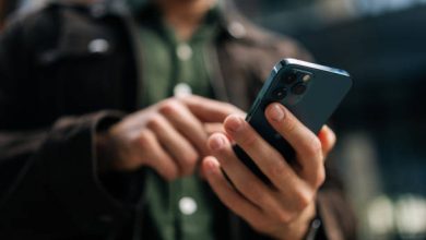 Person holding and using a blue smartphone outdoors, focusing on the device in their hands.