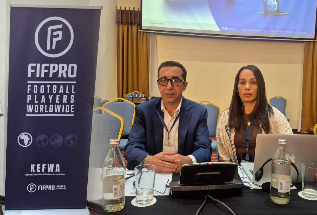 Two panelists sit at a conference table with microphones; a FIFPRO banner stands to the left.