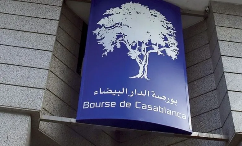 123 | MCG24 | موقع إلكتروني مغربي شامل متجدد على مدار الساعة Blue vertical sign with a white tree logo and Arabic text, plus 'Bourse de Casablanca' in French, mounted on a gray stone wall.