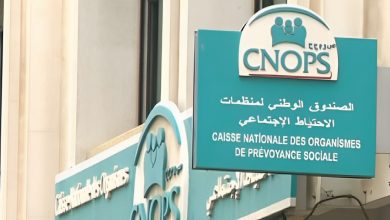 Signboard for CNOPS (Caisse Nationale des Organismes de Prévoyance Sociale) in teal with Arabic and French text on a building façade.