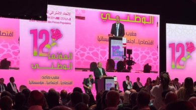 68f271226978e-668x501 | MCG24 | موقع إلكتروني مغربي شامل متجدد على مدار الساعة Speaker at a podium on a bright pink stage with Arabic text and a large '12' rose logo; crowded audience watching.