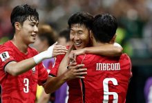 Three football players in red jerseys celebrate with arms around each other on the field, smiling. In the foreground, one wears number 3 and another has '6' on his back with 'INBEOM' visible on the jersey behind him.