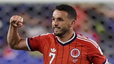 6a2e16f6fb8c0ead8bae3507_default | MCG24 | موقع إلكتروني مغربي شامل متجدد على مدار الساعة Footballer in a red jersey with number 7, fist raised in celebration during a match on the field.