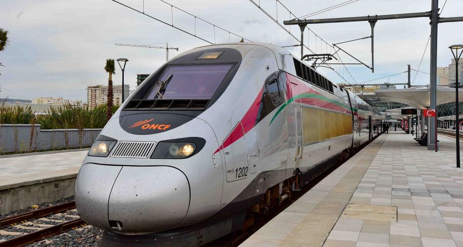 High-speed train at a platform, with overhead electric lines and a modern white exterior featuring pink and green stripes and the ONCF logo on the front.