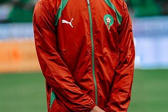 Achraf_Hakimi_ | MCG24 | موقع إلكتروني مغربي شامل متجدد على مدار الساعة Moroccan national football team player wearing a red-green training jacket on a soccer field.