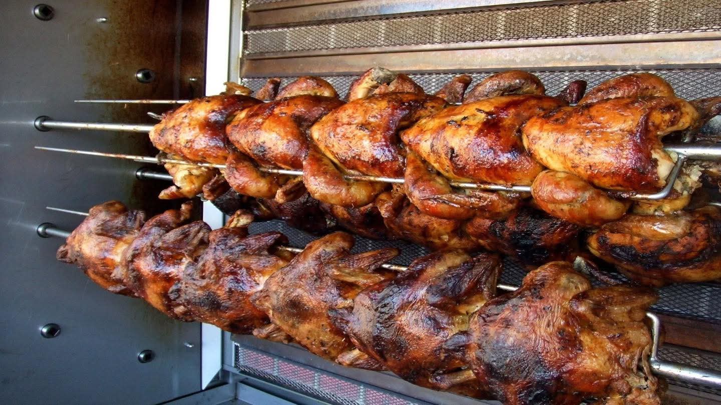 FB_IMG_1781555331114 | MCG24 | موقع إلكتروني مغربي شامل متجدد على مدار الساعة Rows of roasted chickens on rotisserie spits inside a commercial grill, glossy and browned.