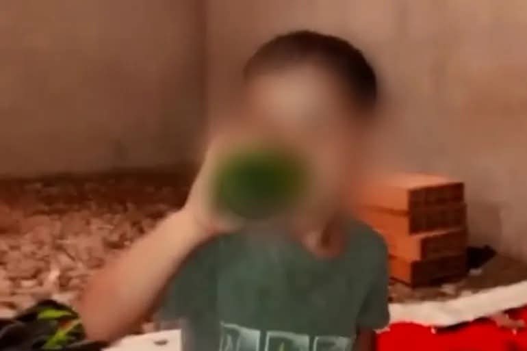 FB_IMG_1781557926180 | MCG24 | موقع إلكتروني مغربي شامل متجدد على مدار الساعة Blurred person wearing a gray shirt drinking from a green bottle in a cluttered room with cardboard boxes and a red blanket.