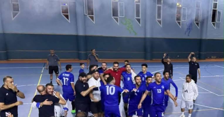 IMG-20260607-WA0110 | MCG24 | موقع إلكتروني مغربي شامل متجدد على مدار الساعة Indoor sports gym with a blue-clad team celebrating in a huddle after a game on a blue court with white lines.