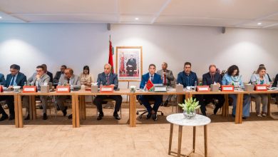 IMG-20260608-WA0098 | MCG24 | موقع إلكتروني مغربي شامل متجدد على مدار الساعة Formal meeting with diverse officials seated along a long conference table; Moroccan flag and framed portrait visible in back.