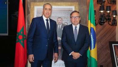 IMG-20260611-WA0164 | MCG24 | موقع إلكتروني مغربي شامل متجدد على مدار الساعة Two men in dark suits posing for a photo indoors, with the Moroccan flag on the left and the Brazilian flag on the right.