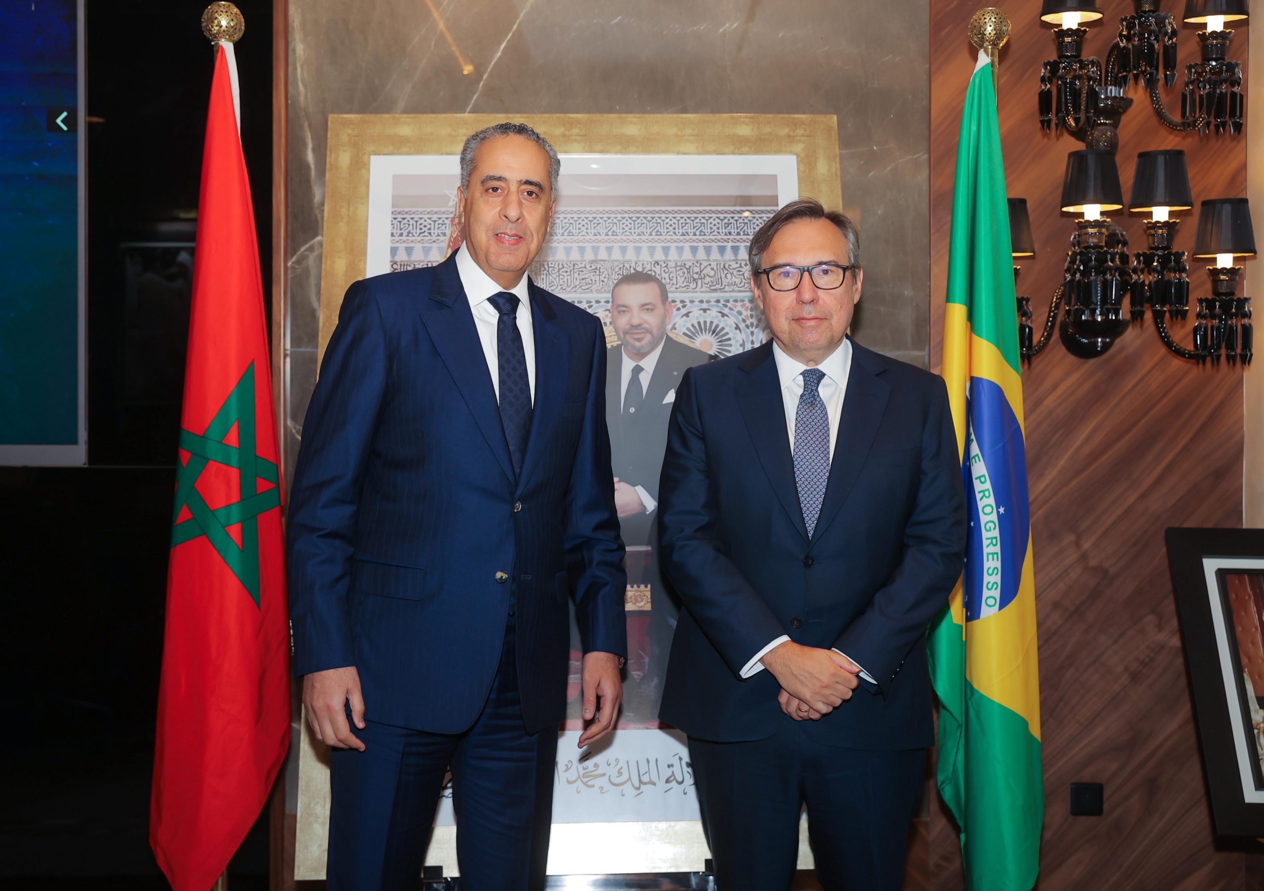 IMG-20260611-WA0164 | MCG24 | موقع إلكتروني مغربي شامل متجدد على مدار الساعة Two men in dark suits posing for a photo indoors, with the Moroccan flag on the left and the Brazilian flag on the right.