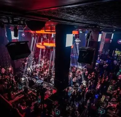 IMG-20260614-WA0100 | MCG24 | موقع إلكتروني مغربي شامل متجدد على مدار الساعة Bird's-eye view of a crowded nightclub with a stage, dancing crowd, and red/orange stage lighting.