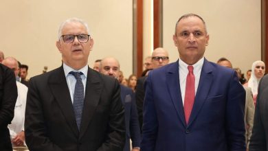 IMG-20260615-WA0096 | MCG24 | موقع إلكتروني مغربي شامل متجدد على مدار الساعة Two men in business suits standing at a formal event, with a crowd of attendees behind them in a conference hall.
