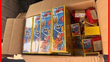 Open cardboard box filled with brightly colored toy boxes featuring cartoon characters.