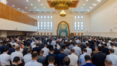IMG-20260619-WA02252 | MCG24 | موقع إلكتروني مغربي شامل متجدد على مدار الساعة Large crowd of men praying in a mosque hall, facing an ornate turquoise-tiled mihrab with arches and gold chandeliers overhead.