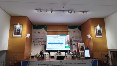IMG_20260620_124419 | MCG24 | موقع إلكتروني مغربي شامل متجدد على مدار الساعة Conference stage with panelists seated at a long table, banners in Arabic behind them and portraits on either side of the walls.