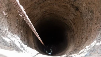 Puits-a-eau | MCG24 | موقع إلكتروني مغربي شامل متجدد على مدار الساعة Deep vertical well shaft with a rope stretched along the left side descending into darkness.