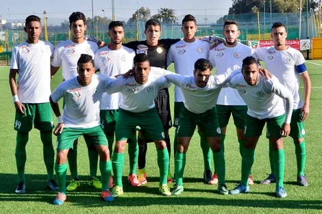 Rcaune_831510976 | MCG24 | موقع إلكتروني مغربي شامل متجدد على مدار الساعة Soccer team posing for a group photo on a grassy field, players in white jerseys and green shorts lined up in two rows before a match.