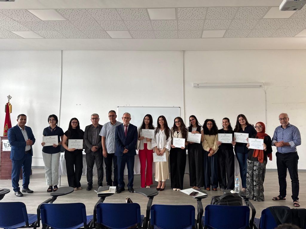 WhatsApp Image 2026-06-04 at 164728 | MCG24 | موقع إلكتروني مغربي شامل متجدد على مدار الساعة Group of people standing in a line, each holding certificates, posing for a photo in a bright room.