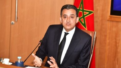 Younes-Idrissi-Kaitouni-508x300-508x300-1 | MCG24 | موقع إلكتروني مغربي شامل متجدد على مدار الساعة Man in a dark suit speaks at a desk with a microphone, Moroccan flag visible in the background behind him.