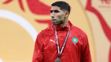 afp_696da04d0cba-1768792141 | MCG24 | موقع إلكتروني مغربي شامل متجدد على مدار الساعة Man in a red track jacket with a medal on a lanyard around his neck, standing at a sports event background.