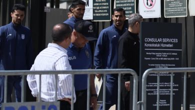 Police officers in blue uniforms behind metal barricades outside a consular services sign area, Turkish 'POLIS' lettering visible in foreground.