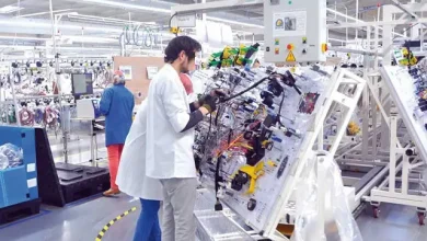 cablagejpg | MCG24 | موقع إلكتروني مغربي شامل متجدد على مدار الساعة Technician in a white coat and mask repairing a complex electrical control panel on an assembly line in a bright factory.