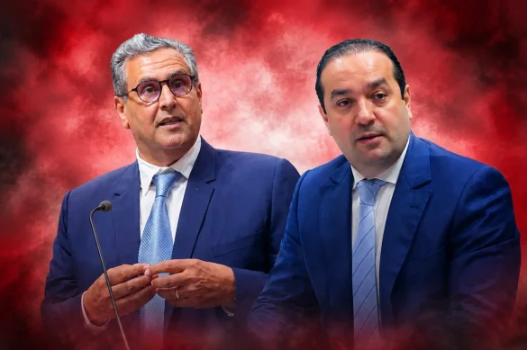 chaouki-1-585x389 | MCG24 | موقع إلكتروني مغربي شامل متجدد على مدار الساعة Two men in dark blue suits stand at a podium with a microphone against a red smoky background, speaking to an audience.