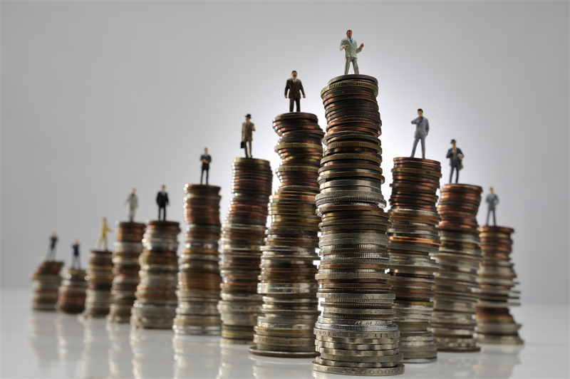 fortune-plus-riches | MCG24 | موقع إلكتروني مغربي شامل متجدد على مدار الساعة Miniature businesspeople stand on stacked coins of varying heights, illustrating the financial ladder and progression.