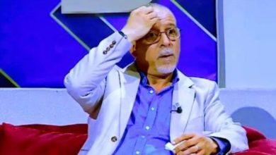 images | MCG24 | موقع إلكتروني مغربي شامل متجدد على مدار الساعة Man on a TV talk show sits on a red couch, hand on forehead, wearing a light blazer and glasses.