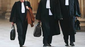 images 22 | MCG24 | موقع إلكتروني مغربي شامل متجدد على مدار الساعة Three people in black legal robes with white tabs walk together, each carrying a bag or briefcase outside a building edge of a courthouse.