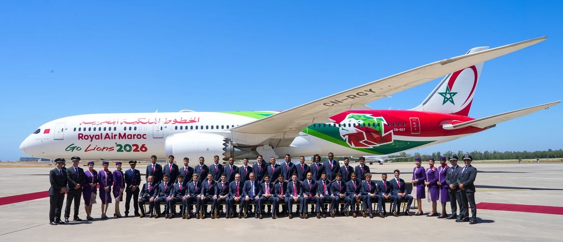 Royal Air Maroc aircraft on the tarmac with a large group of crew members posing in front under a clear blue sky, tan-red banners visible.