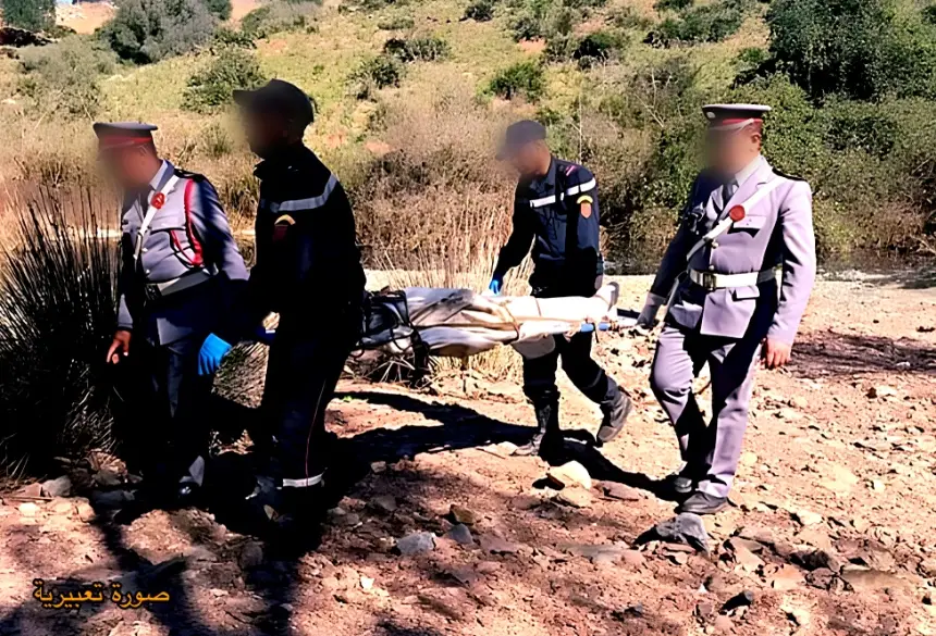 jota_1759924285 | MCG24 | موقع إلكتروني مغربي شامل متجدد على مدار الساعة Rescue workers in uniform transport a body on a stretcher across rocky, arid terrain; faces blurred.